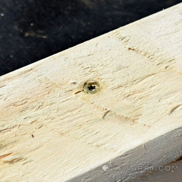 A close up of a screw in a board. 
