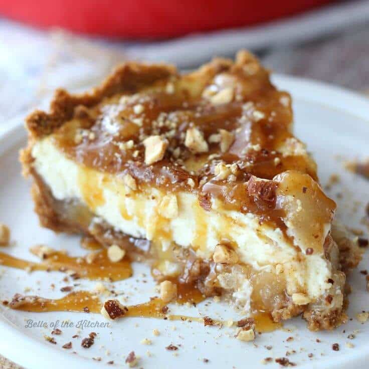 a slice homemade Caramel Apple Cheesecake on a graham cracker crust on a white plate