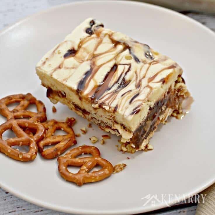 A single slice of Caramel Fudge Ice Cream Cake with a pretzel crust! and a few bite-sized pretzels on the side. 