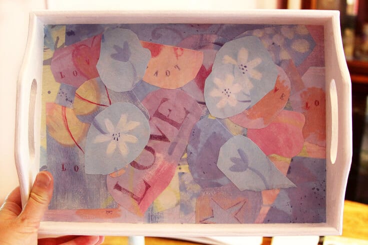 A white wooden tray with colorful pieces of scrapbook paper glued to the inside. 