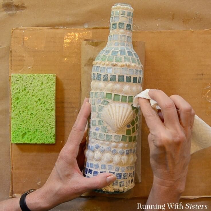 Learn how to make a mosaic wine bottle with shells and tiles! We'll show how to glue the tiles and mix the grout with a video and written steps!