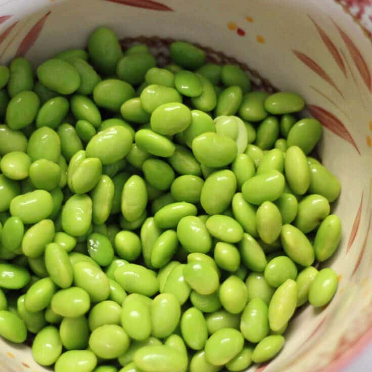 a bowl full of raw edamame, or soy beans 