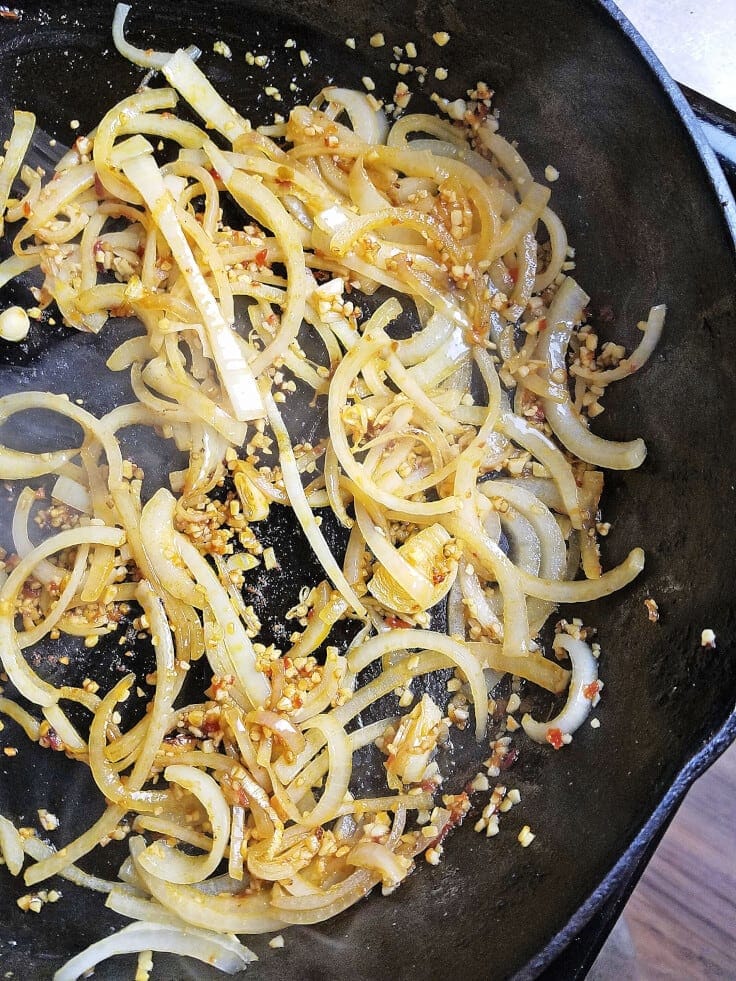 Sautéed onions and garlic in a black skillet