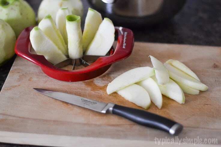 using an apple slicers to cut apples on a wooden cutting board