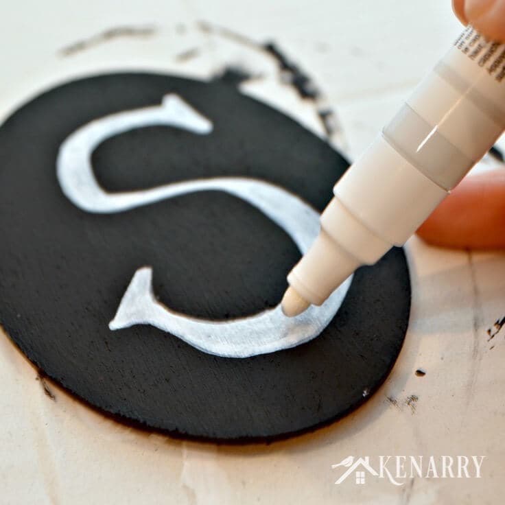 Painting the unfinished oval wood sign black with a white letter S