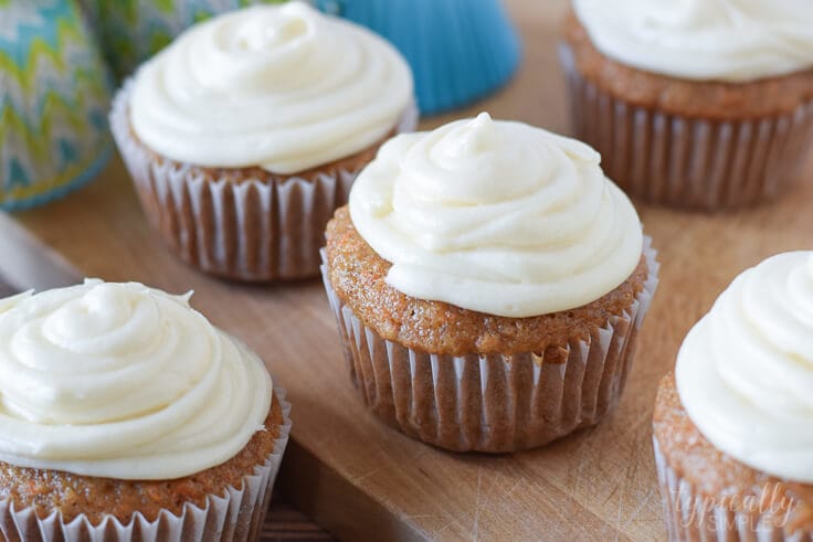 carrot cake cupcakes with cream cheese frosting on a wooden surface