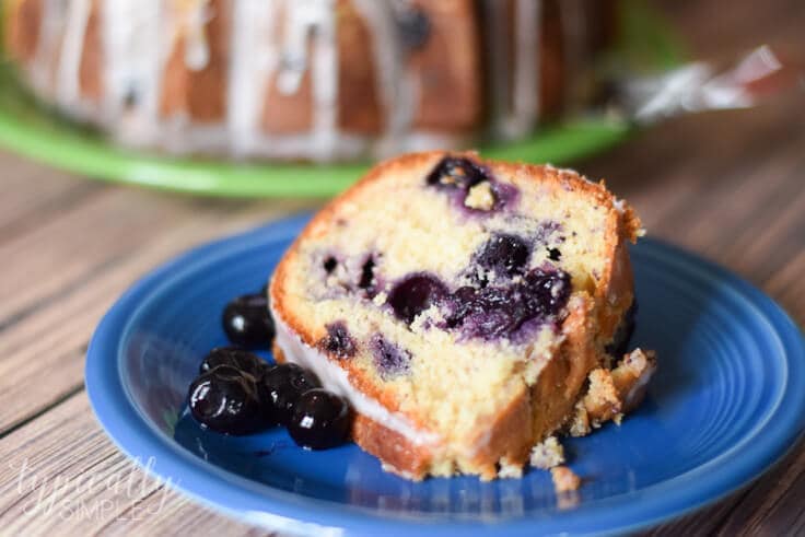 slice of lemon blueberry pound cake on a plate with a bundt cake in the background