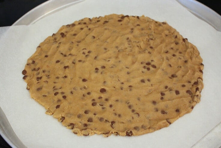 chocolate chip cookie dough rolled out into the shape of a pizza