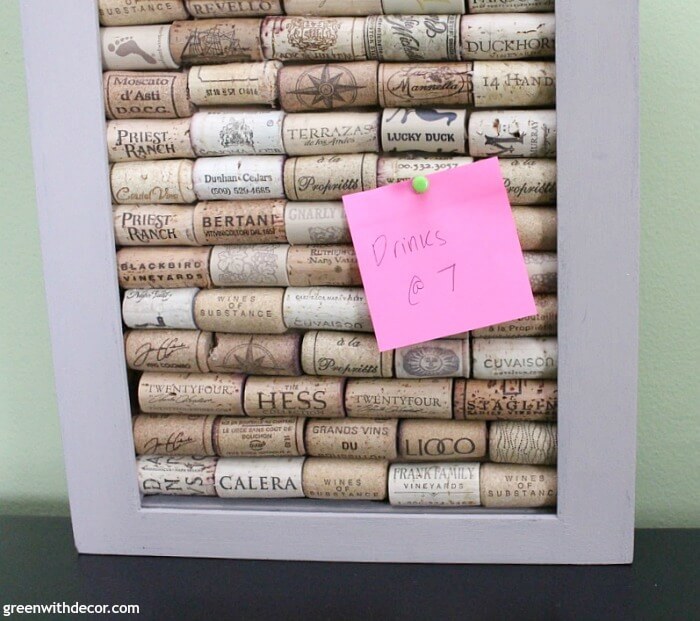 A close up of a pink sticky note pinned to a cork board made out of wine corks. 
