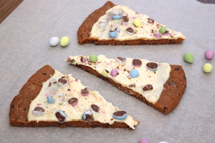 slices of an Easter egg cookie pizza on parchment paper