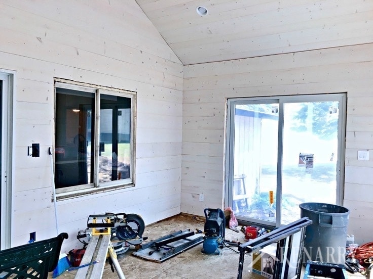 White washed pine plank walls installed in a sunroom as part of a cottage update. These shiplap walls give the room a rustic farmhouse style look.