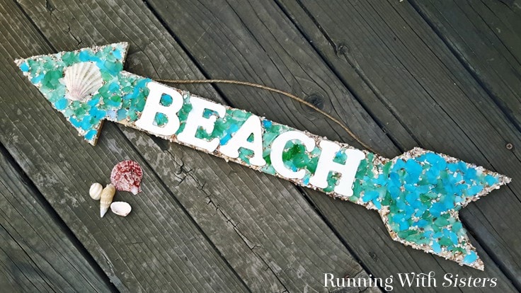Make a beachy mosaic arrow sign without grout. We'll show you how to add sea glass, crushed shells, and sand to make an easy mosaic BEACH sign!