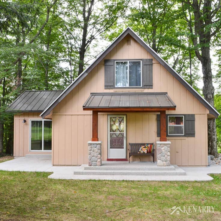 Add craftsman style to an a-frame cottage by adding a front porch with a metal roof, cedar posts, river rock pillars and a mission style bench | home idea | exposed aggregate concrete | a-frame house | outdoors