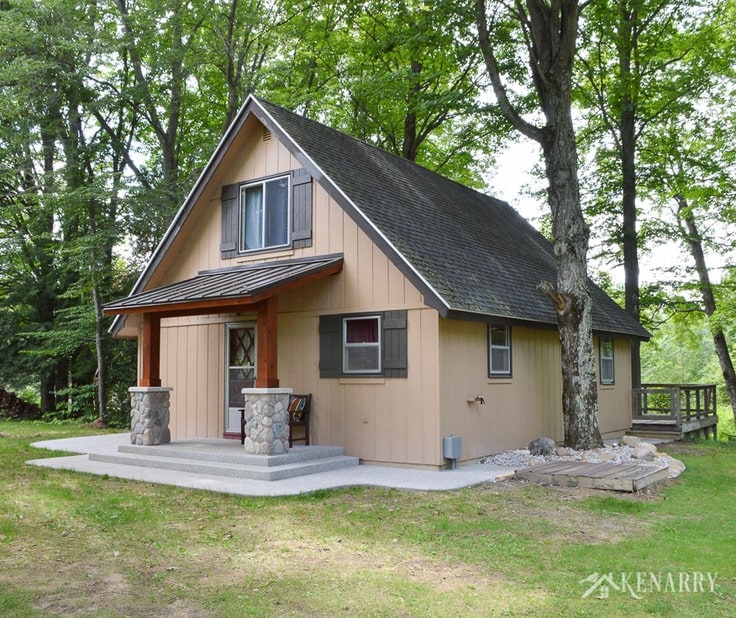 A-frame cottage gets a whole new look with board and batten shutters and a craftsman style porch surrounded by an exposed aggregate patio. river rock pillars | home idea | cedar posts | sloped metal roof
