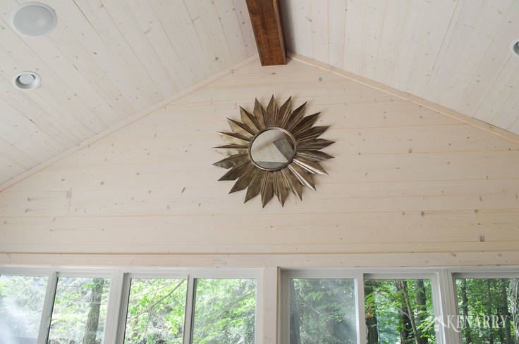 A large metal sunburst mirror adds industrial style to this cottage sunroom with vaulted shiplap ceiling and walls | shiplap walls | plank wall | whitewashed pine wood walls | home decor | home ideas | farmhouse style