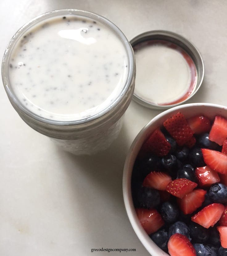 overnight oatmeal in a mason jar with a bowl of strawberries and blueberries
