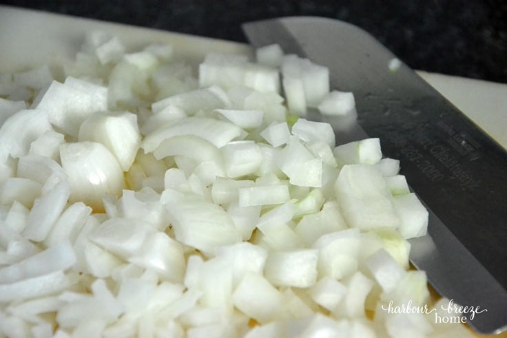 A close-up of a knife and chopped onions