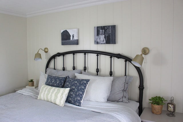A bed with a brass headboard and 2 lamps on the wall 