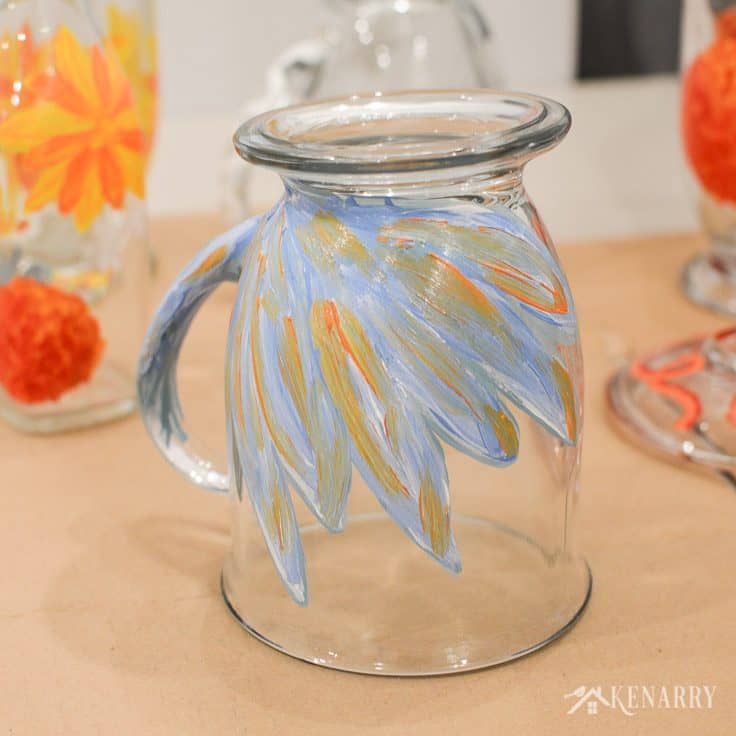 Blue, orange, and white gloss enamel paint mix together to create a beautiful flower design on DIY coffee mugs.