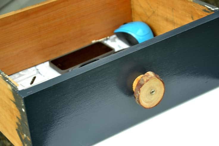picture of navy blue drawer front with a wood slice drawer pull