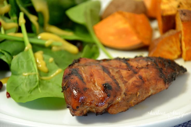 barbecue chicken on white plate along with a green spinach salad and roasted sweet potatoes