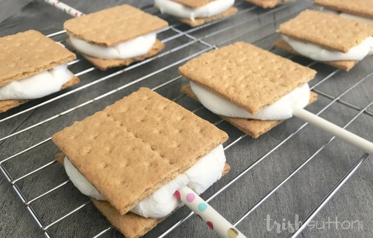 S'mores with paper straws cooling on a wire rack. 