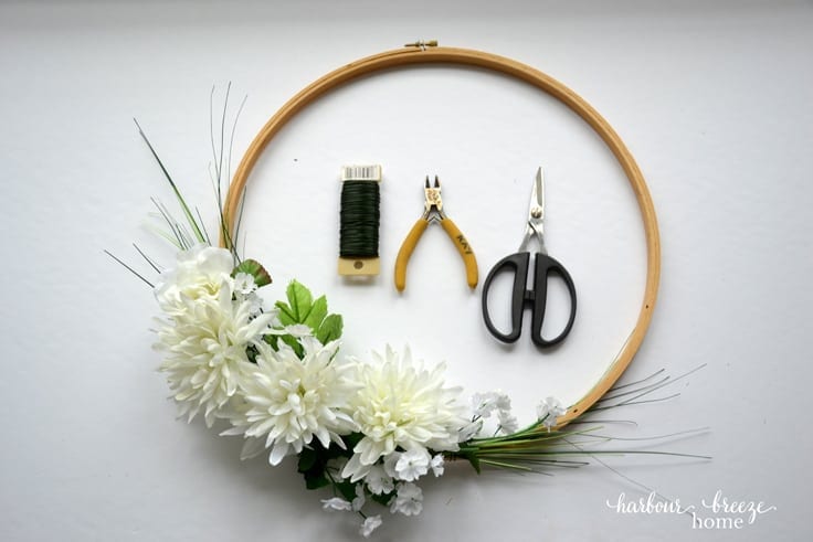 Add small flowers and greenery to fill in an arrangement on an embroidery hoop wreath
