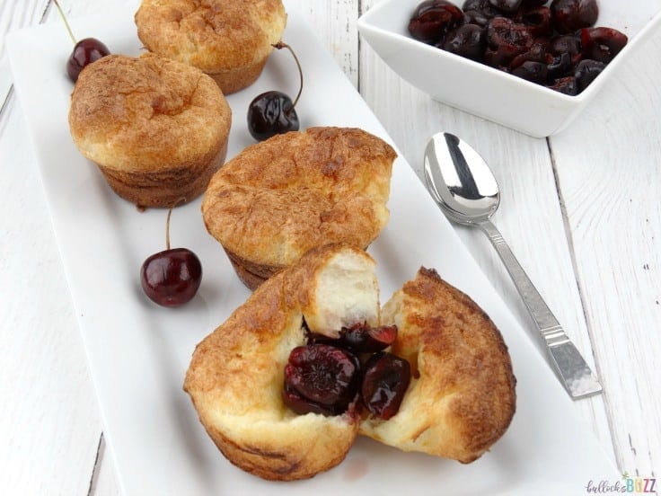 cherry popovers on a white plate with a bowl of cherries