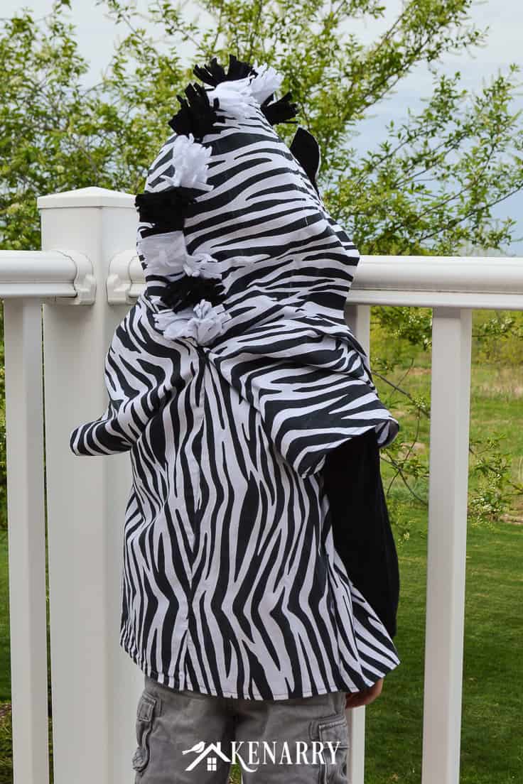 The back of this kids zebra costume shows the fluffy mane made with black and white felt. Learn how to create this zebra costume for a child to wear as a cute Halloween idea or for dress-up clothes. #diyhalloweencostume #halloween #costume #halloween #kidscostumes #diycostumes #kenarry