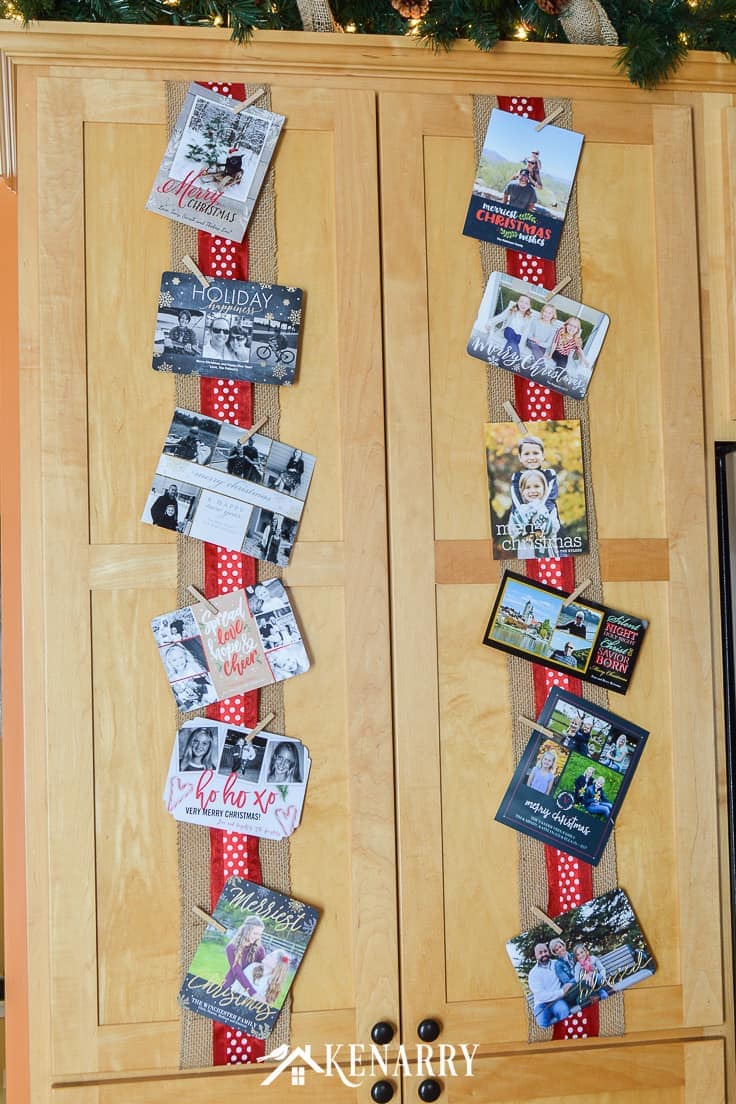 Use wide ribbon, burlap and small clothes pins for displaying Christmas cards on your kitchen cabinets so you can enjoy looking at them throughout the holidays. #christmascards #christmas #kenarry