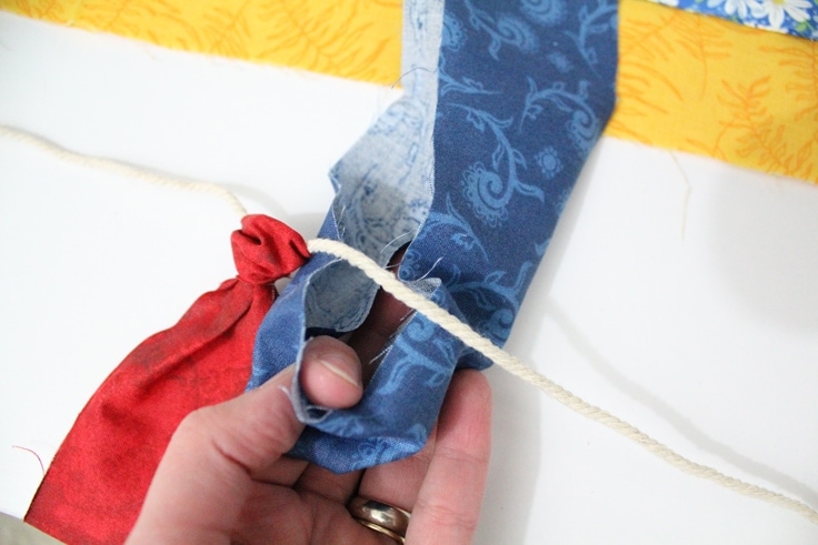 DIY Fabric garland is an easy craft project that uses up fabric scraps from your stash. It’s so simple you’ll want to make it for dressing up windows, decorating for a party, or just to swap out your color scheme for a season.