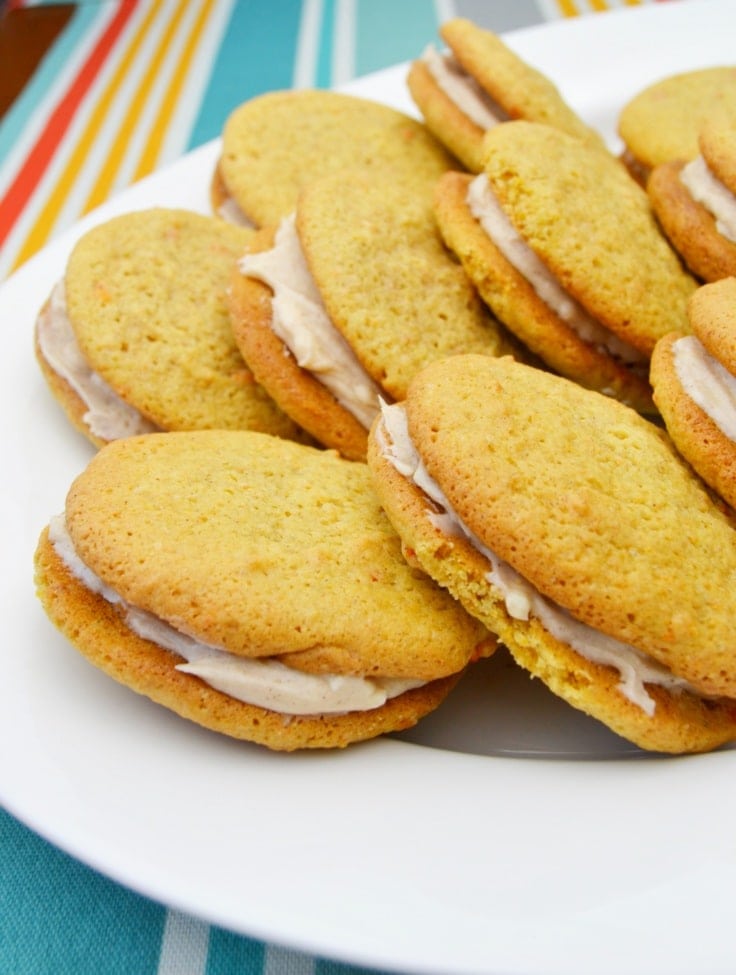 carrot cake cookie sandwiches with cinnamon cream cheese frosting on a plate
