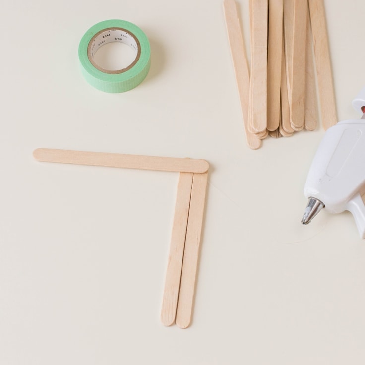 How to make a popsicle stick craft - second step is to glue another stick horizontally on top of the other two sticks.