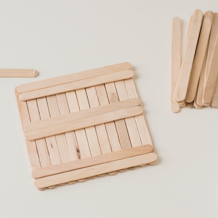 How to make a popsicle stick craft. Fifth step is to flip the coaster over upside down and create a base of perpendicular sticks glued on. 