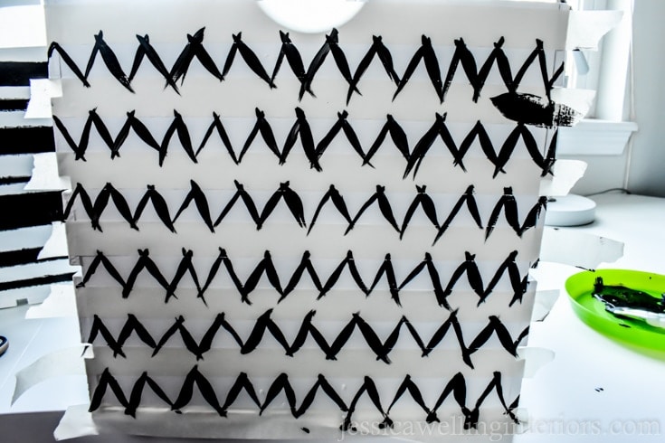 A white wood crate with black chevron painted on it. 