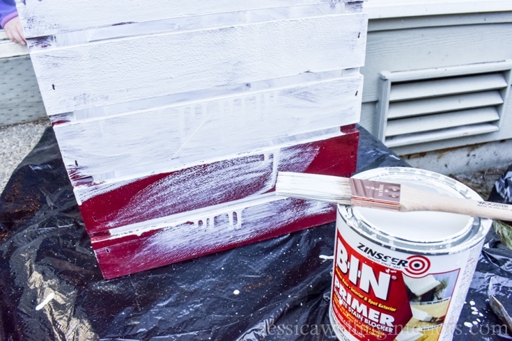 A red crate with white primer paint on the outside.