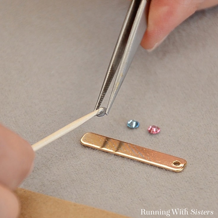 Use tweezers to hold the rhinestone and dab glue on the back. 