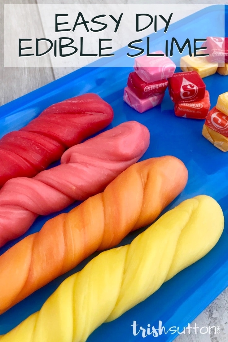 Red, pink, orange and yellow Starburst slime sitting on a bright blue tray with candy pieces.