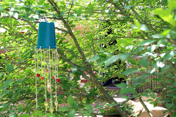 A blue wind chime hanging in a green tree