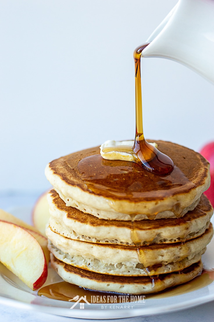 Delicious sweet syrup being poured onto a stack of apple cinnamon pancakes made with applesauce