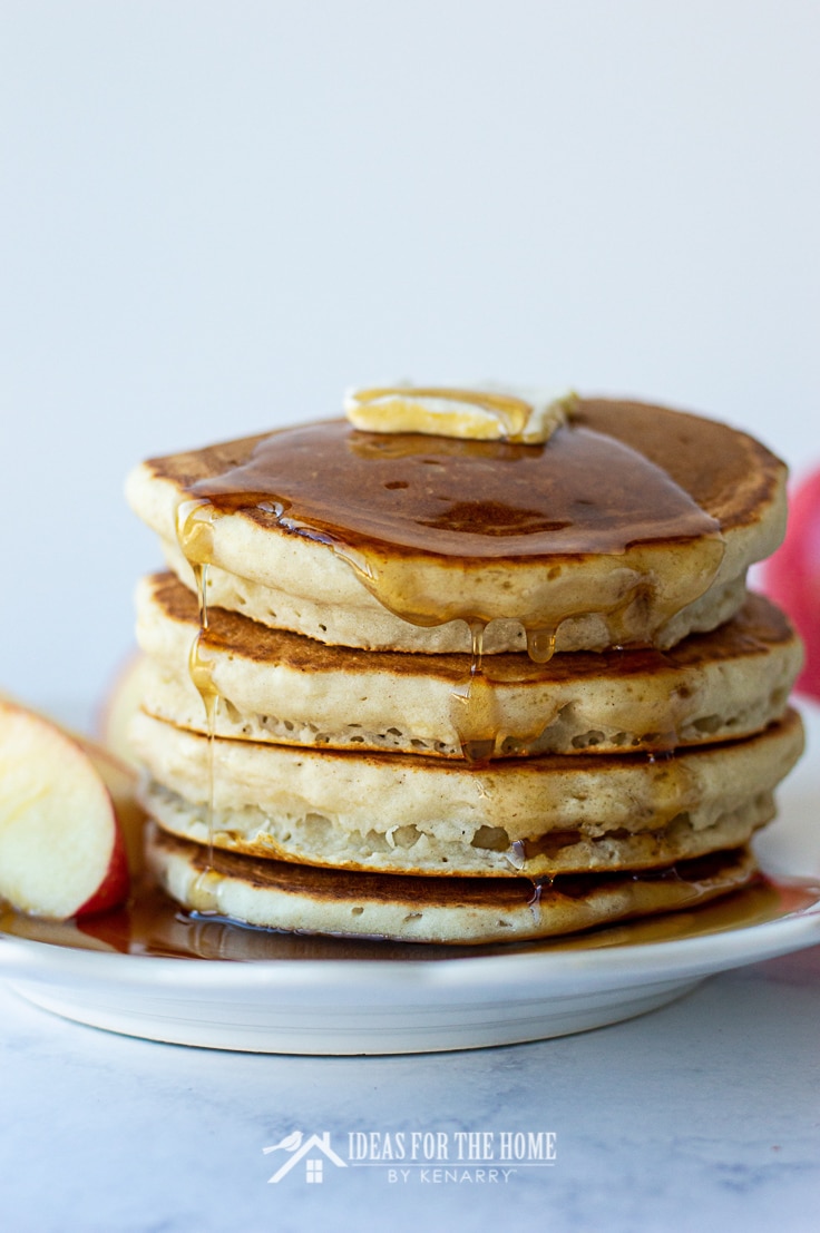 Maple syrup pouring down the sides of apple cinnamon pancakes