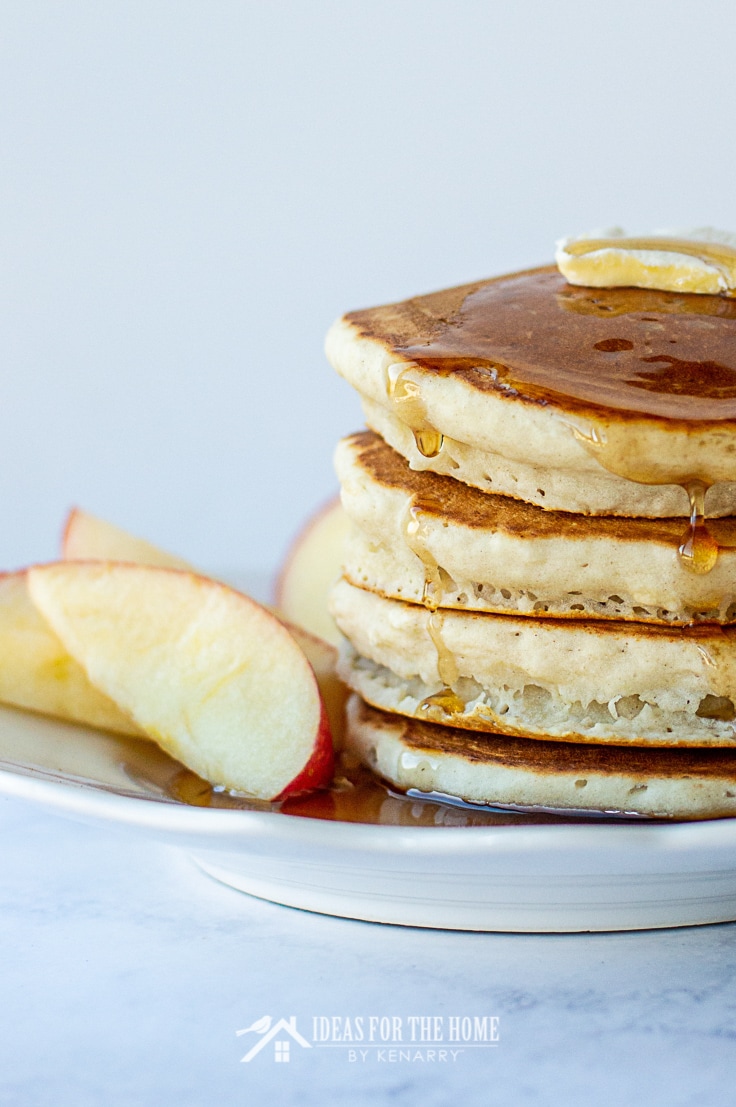 A stack of cinnamon apple pancakes topped with butter and maple syrup