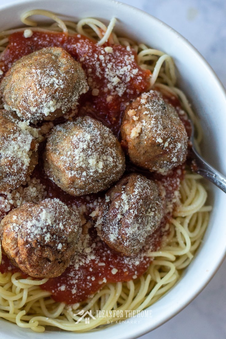 Overhead close-up of Italian meatballs and tomato sauce on a bowl full of pasta