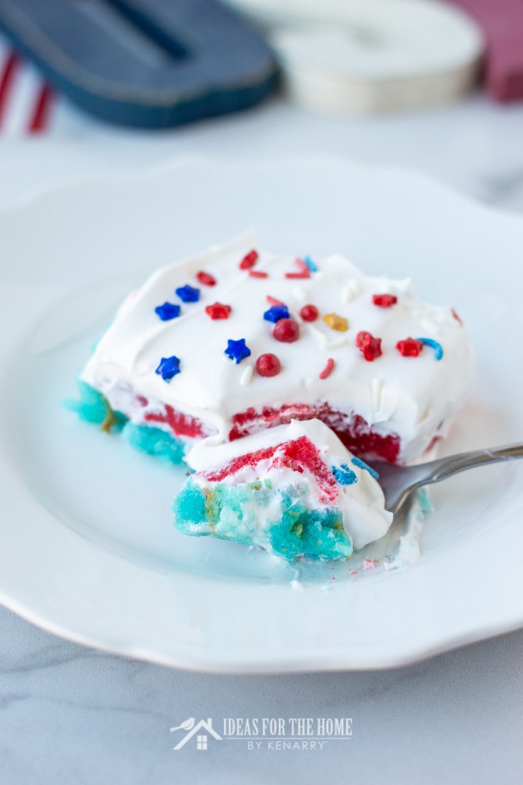 A fork taking a bite off the corner of a layered cake in red, white and blue colors