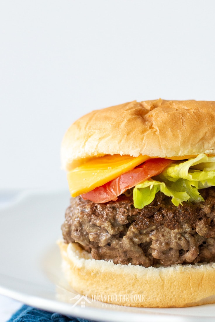 Close up of a meatloaf hamburger on a bun with cheese, tomato and lettuce