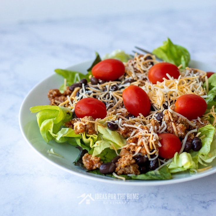 Beef taco salad with crushed nacho chips, black beans, tomatoes, cheese and lettuce
