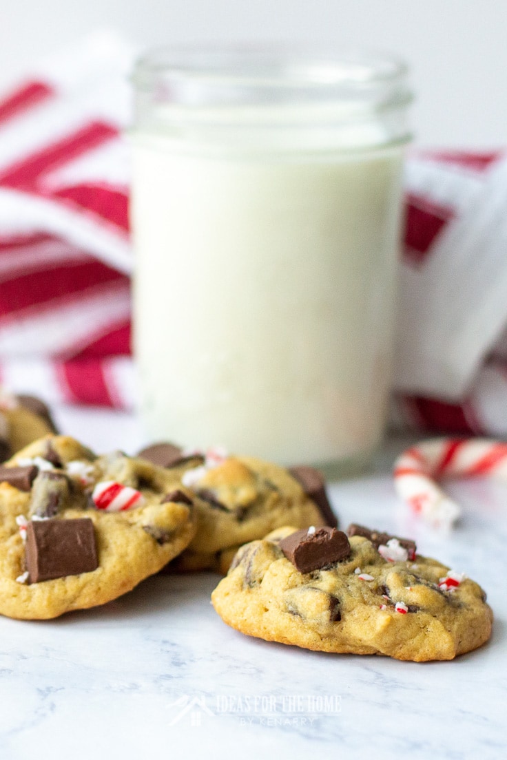 A tall glass of milk with chocolate chip cookies topped with crushed peppermint candy