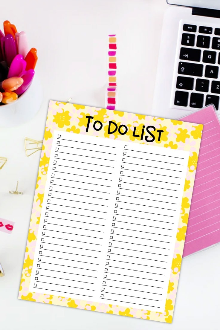 Preview of yellow floral printable to do list on desk with laptop keyboard, pink markers, pink notebook and stationery accessories on a white background.